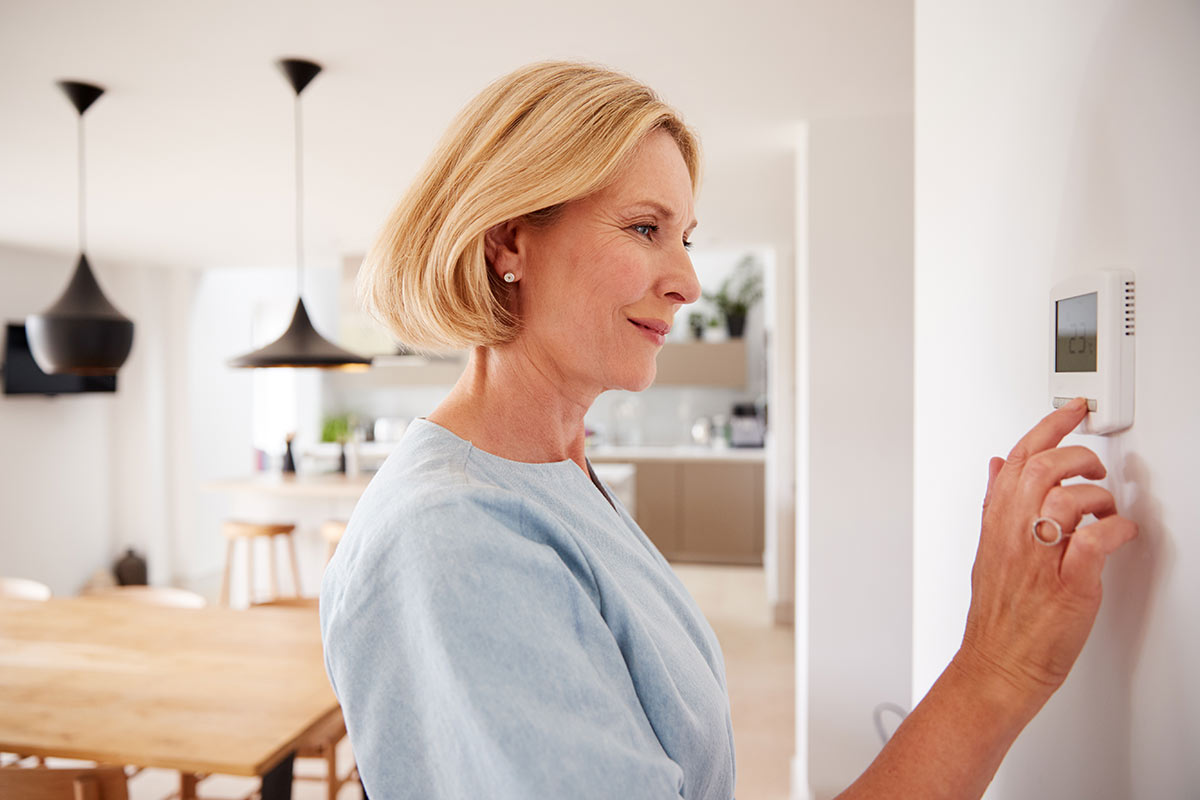 Woman adjusting her thermostat